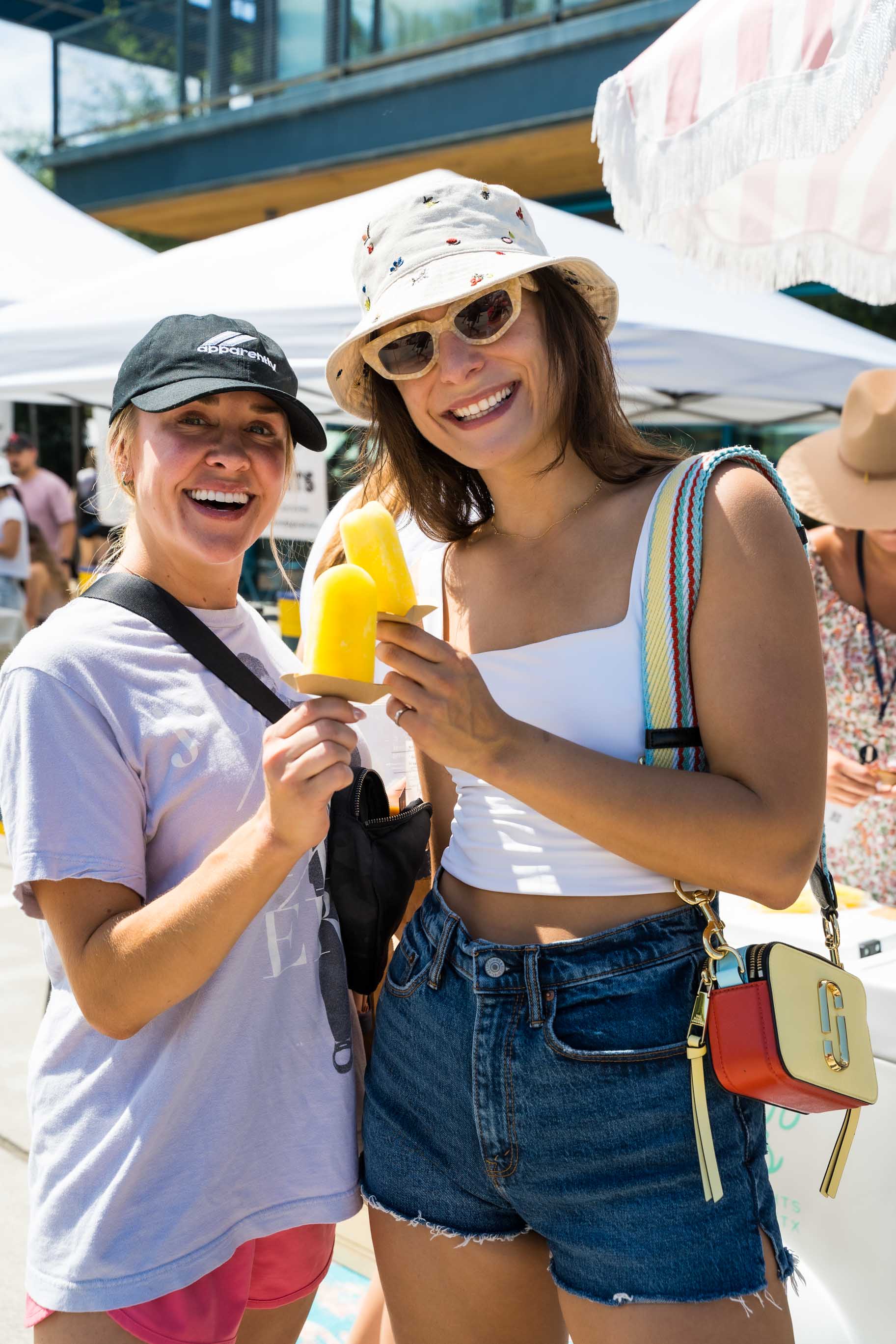 Two woman having a Pineapple vegan friendly ice popsicles at a festival.