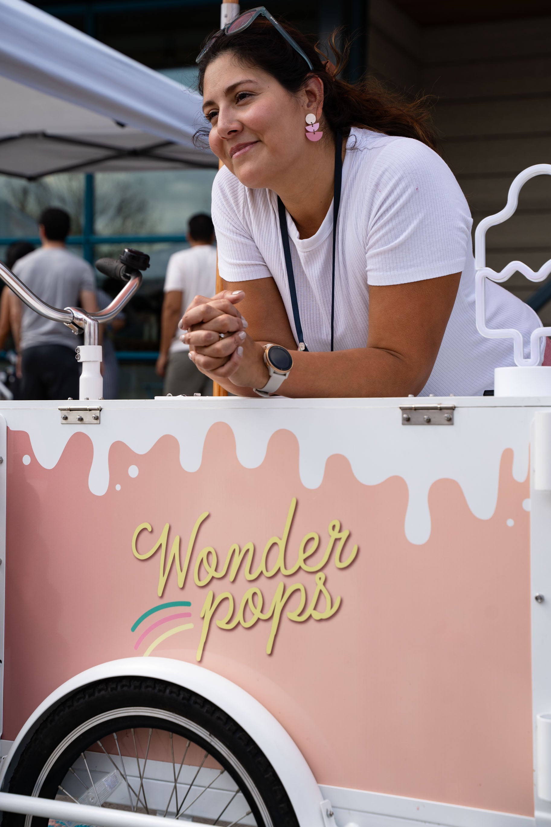 Woman owned business leaning on vintage frozen dessert cart. Wonder Pops logo.