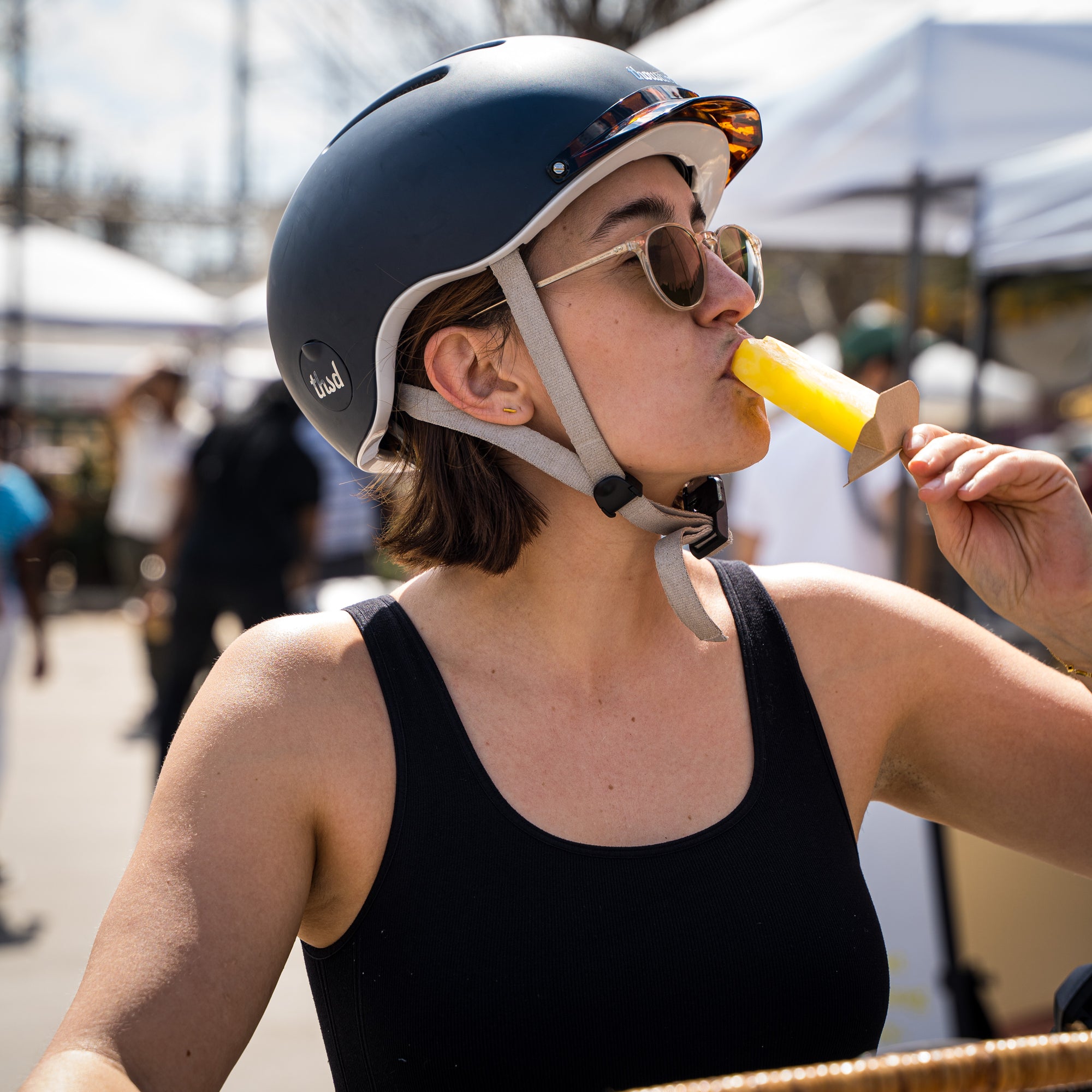 Woman on a bicycle tasting a vegan ice pop.