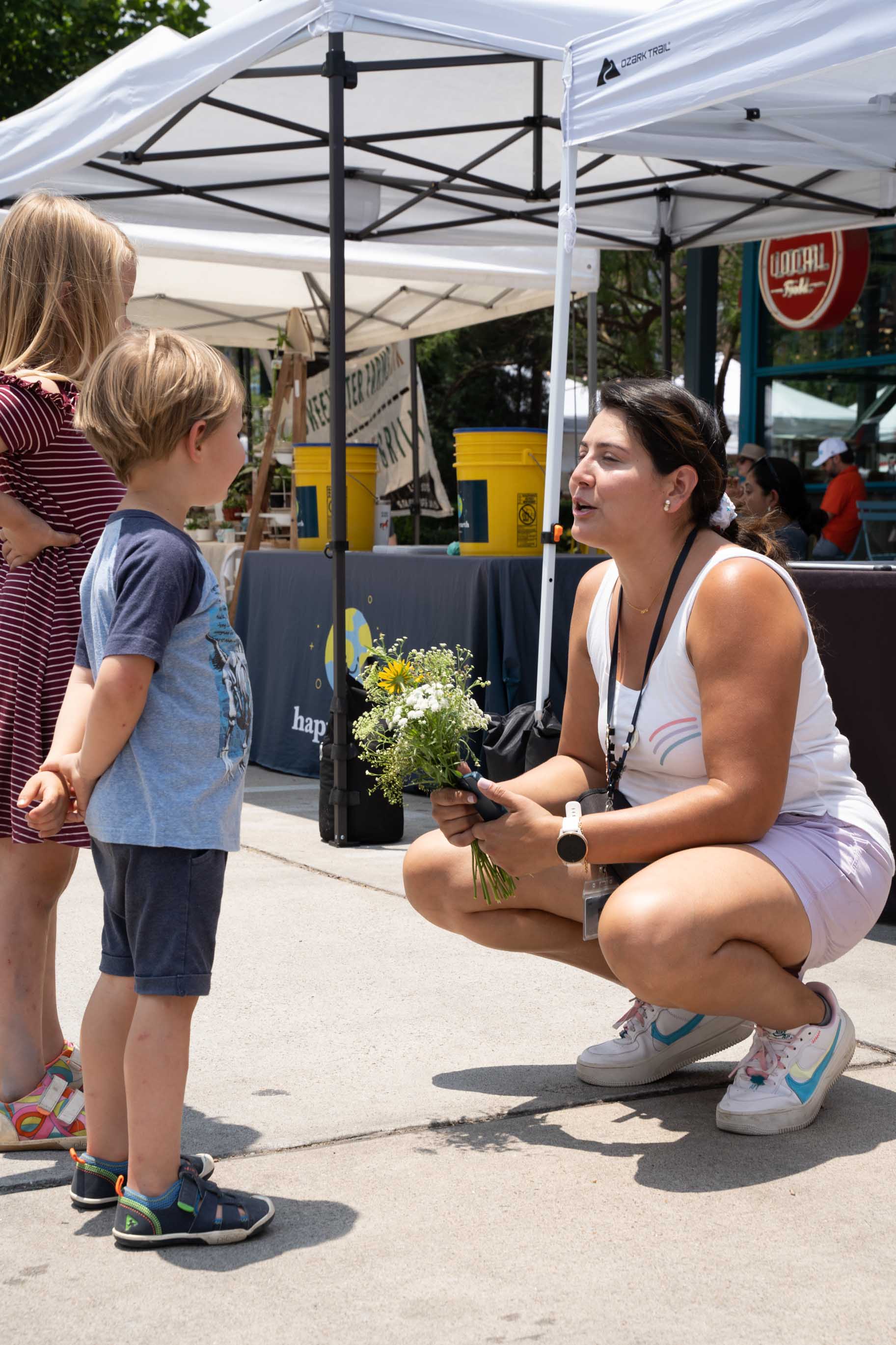 Two kids giving flowers to woman.