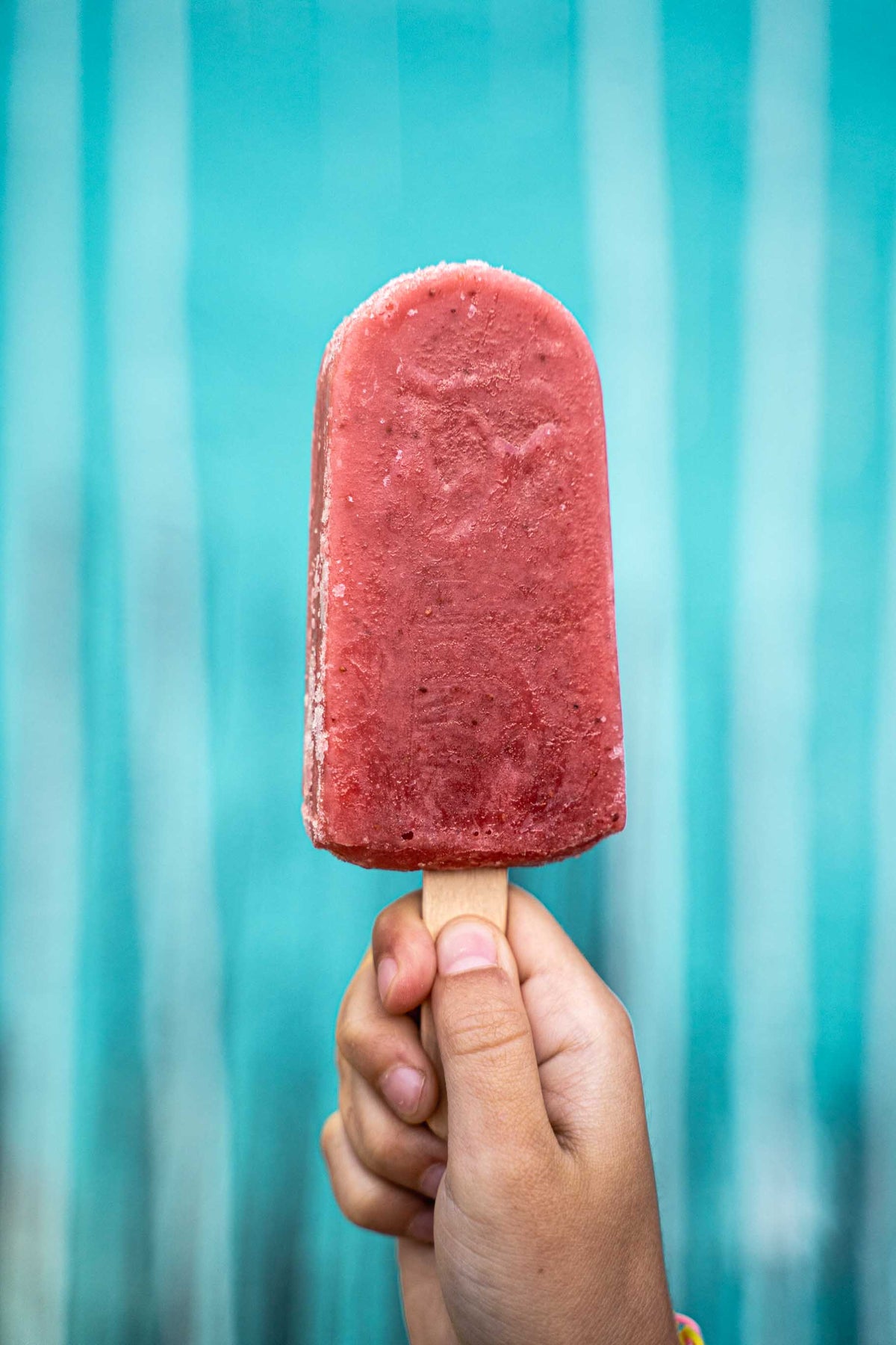 Child hand holding a handcrafted ice popsicle.