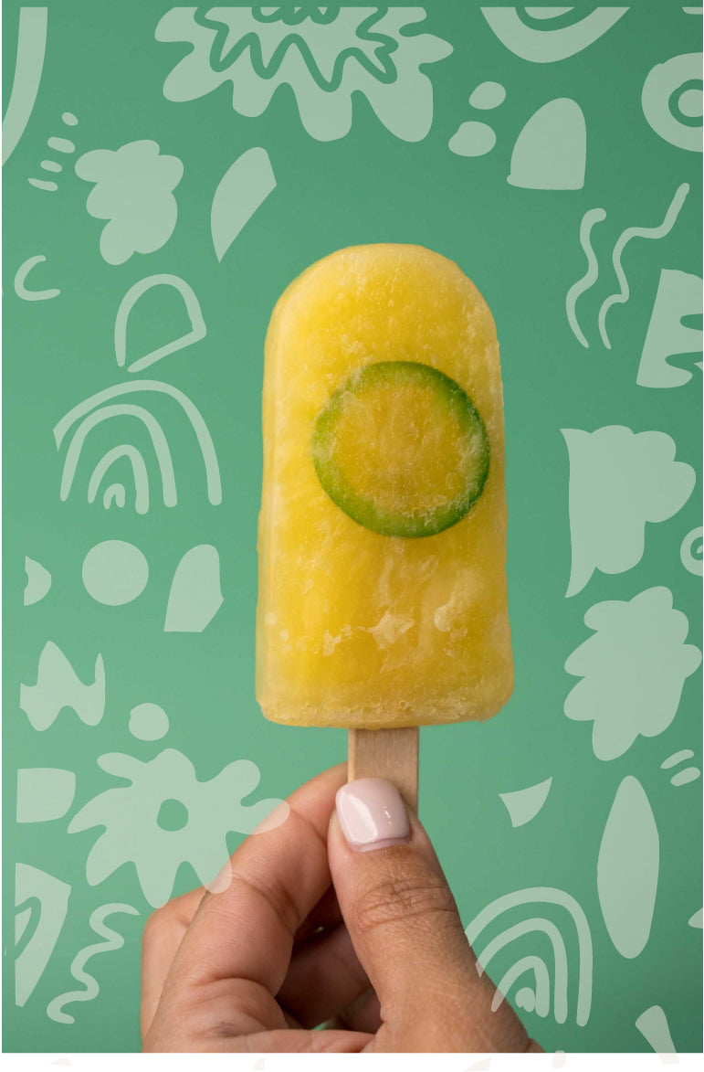 Pineapple artisan ice pop held by a woman hand. Background with flower doodles.