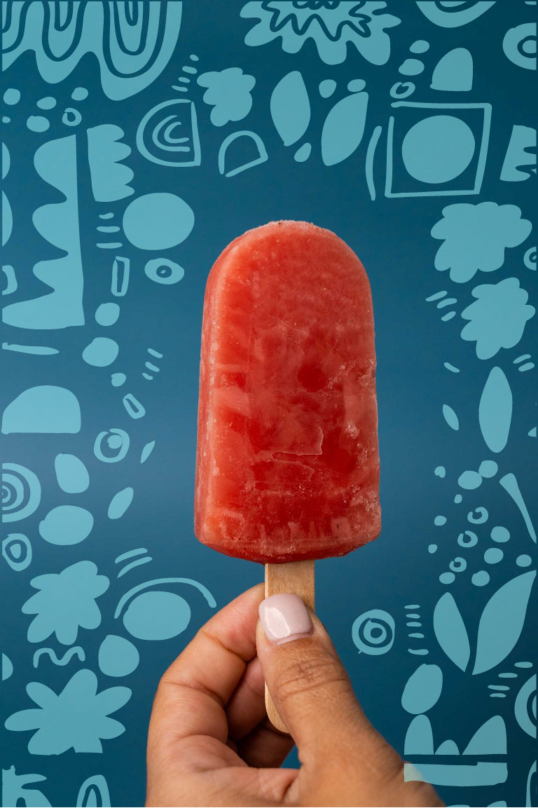 Watermelon handmade ice pop held by a woman hand. Background with flower doodles.