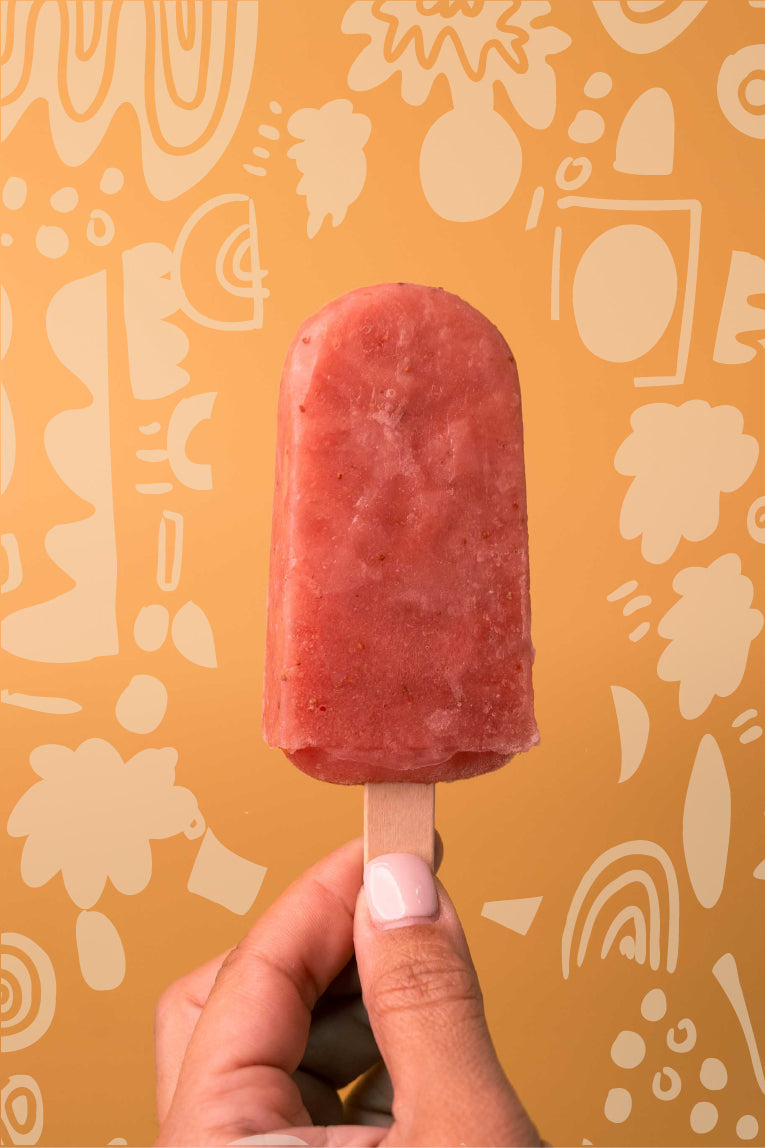 Strawberry natural ice pop held by a woman hand. Background with flower doodles.